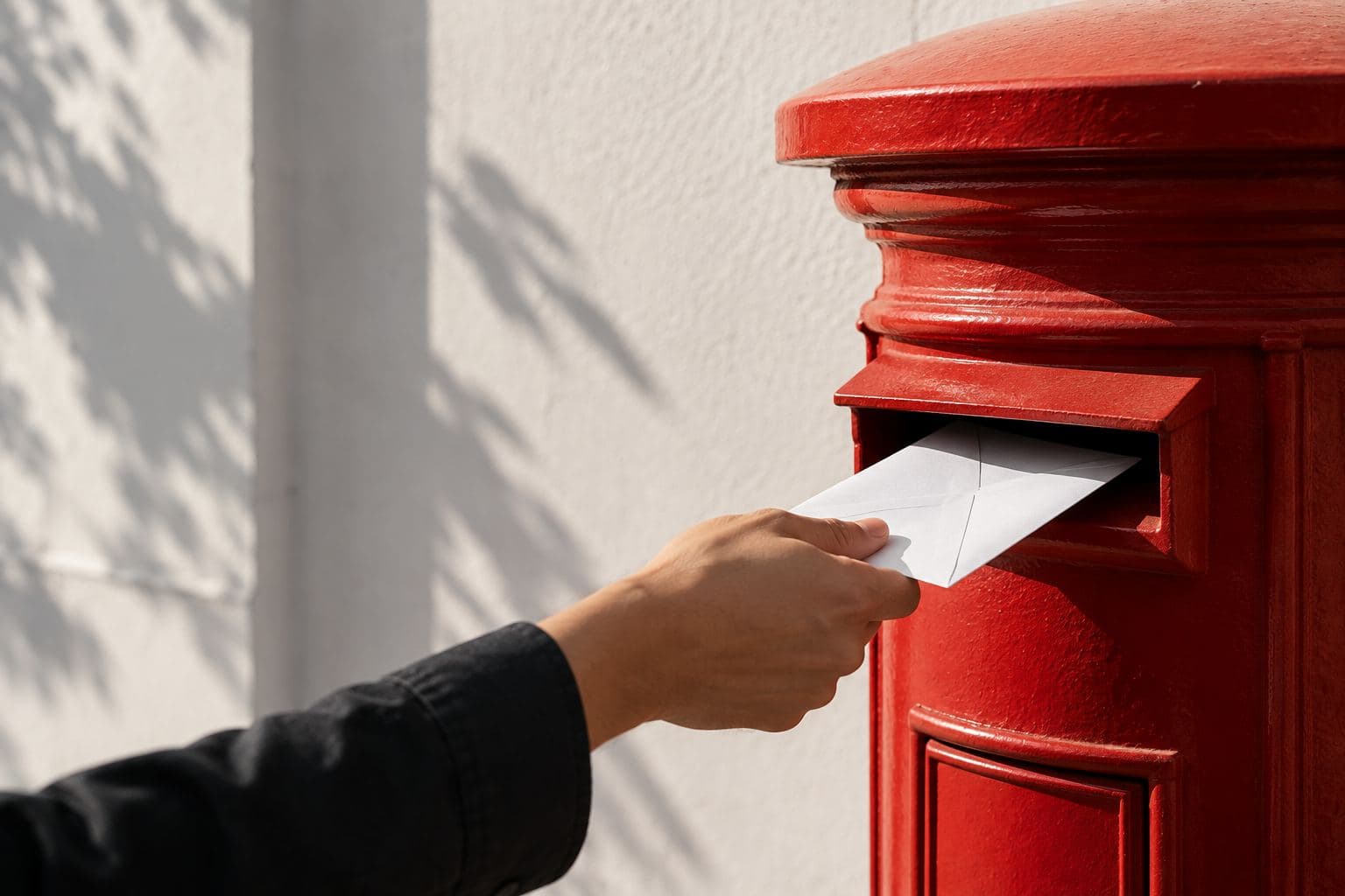 A hand posting a sealed envelope.