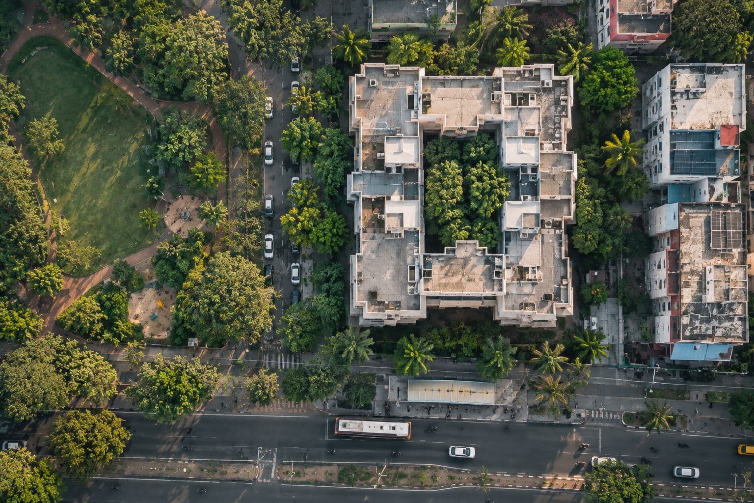 One apartment block from above, with a park, shops and a bus stop around it.