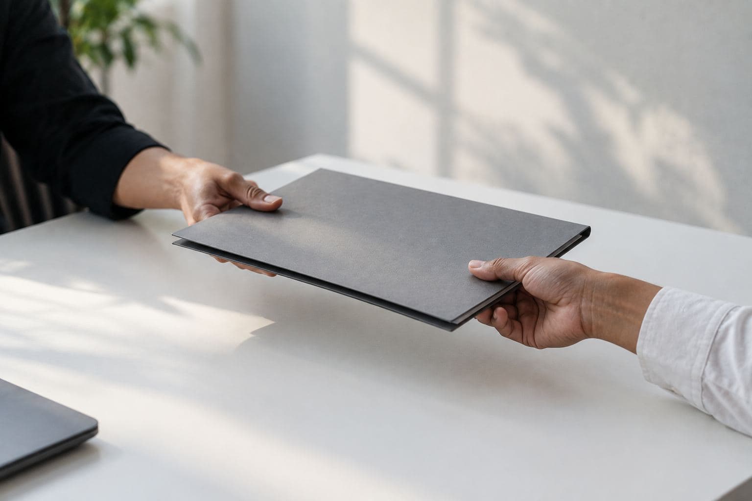 A closed folder handed across a table.